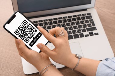 Masada QR kodlu akıllı telefonu olan bir kadın var, yakın plan.