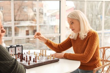 Kocasıyla mutfakta satranç oynayan olgun bir kadın.