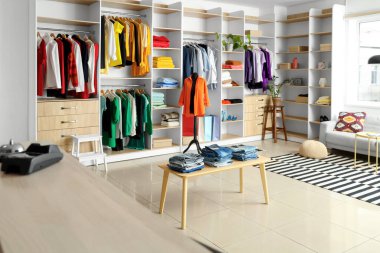 Raflı butiğin içi, şık kıyafetler ve mankenlerle dolu.