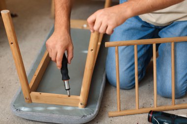 Tornavidalı genç adam bankı evde kuruyor, yakın plan.