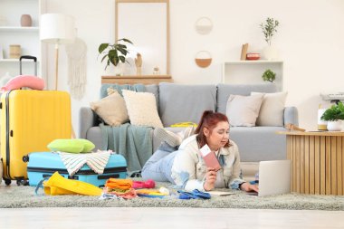 Pasaportu olan genç bir kadın evde dizüstü bilgisayar kullanıyor. Seyahat kavramı