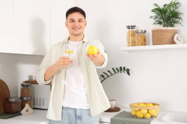 Mutfakta bir bardak limonlu su olan genç bir adam.