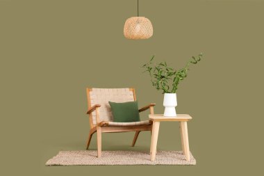 Vazoda bambu saplı masa, yeşil arka planda koltuk ve lamba.