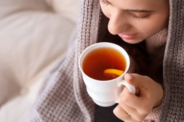 Ekoseli genç bir kadın evde limonlu çay içiyor, yakın plan.