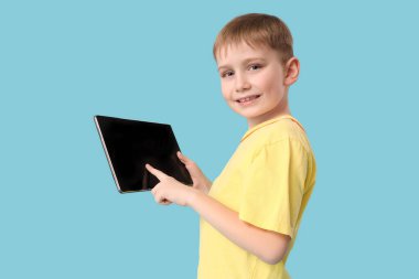 Mavi arka planda boş ekranı olan modern tablet bilgisayar kullanan sevimli küçük çocuk.