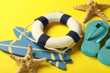 Küçük plaj aksesuarları ve sarı arka planda deniz yıldızları olan kompozisyon