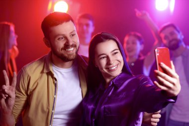 Gece kulübünde selfie çeken mutlu genç çift.