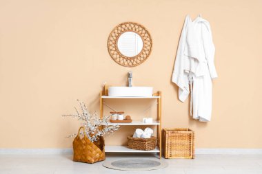 Banyonun iç tarafındaki bej duvarın yanında çiçek açan dallarla dolu bir sepet.