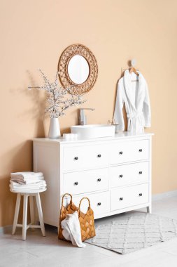 Çiçek açan dalları olan vazolar ve banyonun iç tarafındaki bej duvarın yanındaki çekmecelere batıyor.