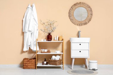 Banyonun içinde raf ünitesi, çekmeceler ve dallı vazo var.