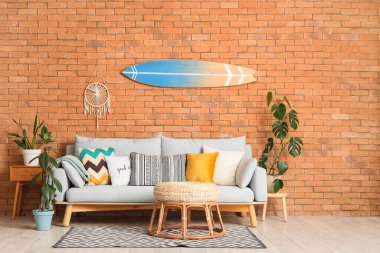 Sörf tahtası, kanepesi ve bitkileri olan bir oturma odası.