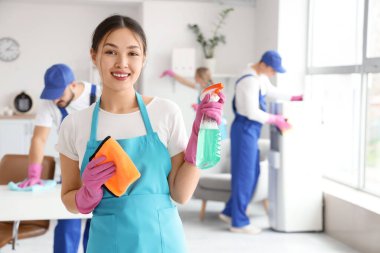 Ofisinde paçavra ve deterjanı olan Asyalı kadın hademe.