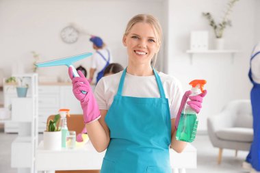 Ofisinde cam sileceği ve deterjanı olan kadın hademe.