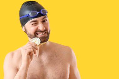 Birincilik madalyası olan erkek yüzücü sarı arka planda yanıp sönüyor.