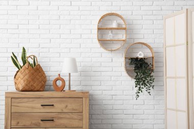 Odadaki çekmecelerin üzerinde bitki ve lamba olan bir sepet.