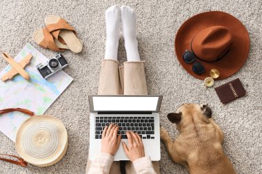 Dizüstü bilgisayarı olan genç bir kadın, sevimli bir Fransız bulldog ve evde gezici aksesuarlar.