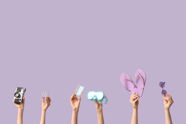 Parmak arası terlikleri, kamera ve leylak arka planda dalış gözlükleriyle mini güverte sandalyeleri tutan kadın eller.