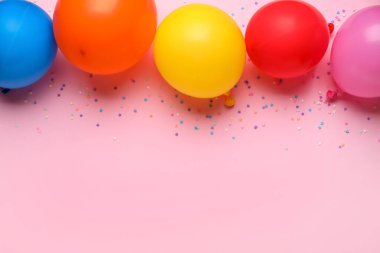 Farklı hava balonları ve pembe arka planda konfeti.