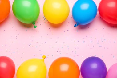 Farklı hava balonlarından yapılmış çerçeve ve pembe arka planda konfeti