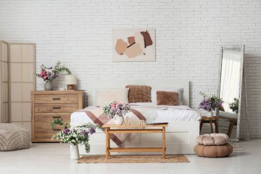 Işıklı yatak odasının içinde çiçekli vazolar.