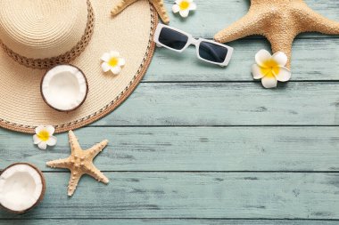 Yeşil ahşap arka planda hindistan cevizi ve plaj aksesuarlarıyla kompozisyon