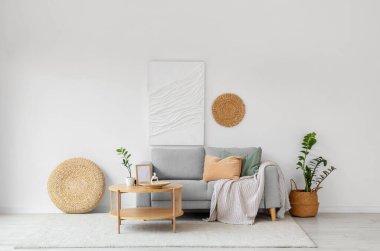 Oturma odasının iç tarafındaki beyaz duvarın yanındaki kanepe ve ahşap sehpa.