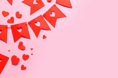 Pembe arka planda kalpleri olan kırmızı kağıt bayraklardan yapılmış çelenkler. Sevgililer Günü kutlaması