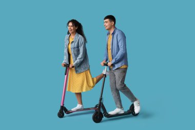 Mavi arka planda modern elektrikli scooter kullanan güzel bir çift.
