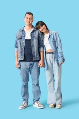 Birbirine aşık genç bir çift mavi arka planda el ele tutuşuyor