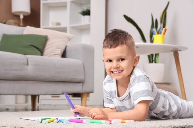 Evde keçeli kalemle çizen küçük çocuk.