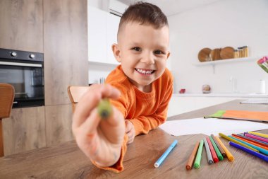 Mutfaktaki masasında keçeli kalemlerle çizen sevimli küçük çocuk.