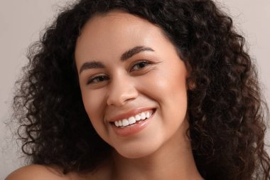 Gri arka planda sağlıklı bir teni olan güzel, mutlu, Afro-Amerikan kadın.