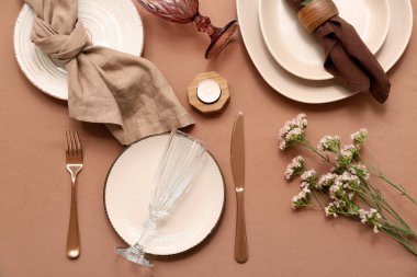 Çingene çiçekleri ve kahverengi arka planda yanan mumlarla güzel bir masa.