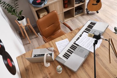 Stüdyoda sentezleyici, dizüstü bilgisayar ve mikrofonlu müzisyen işyeri.