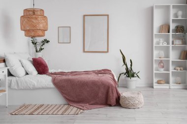 Yatak odasının içinde raf ünitesi, ev bitkileri ve mor battaniye ve ev bitkileri var.