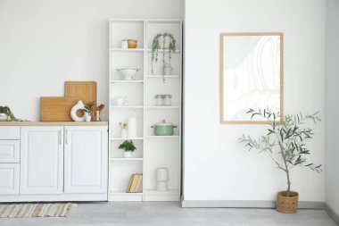 Beyaz tezgahlı, zeytin ağacı ve raf üniteli şık bir mutfak.