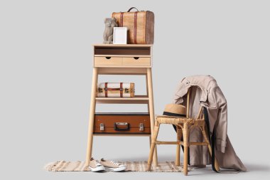 Gri arka planda sandalye, dekor ve klasik bavullu şık makyaj masası.