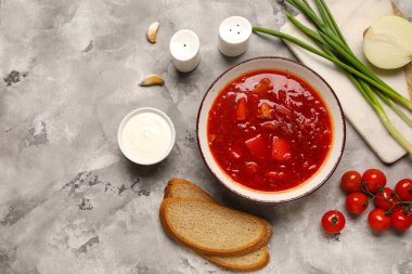 Bir kase lezzetli Ukrayna çorbası ve gri arka planda malzemeler