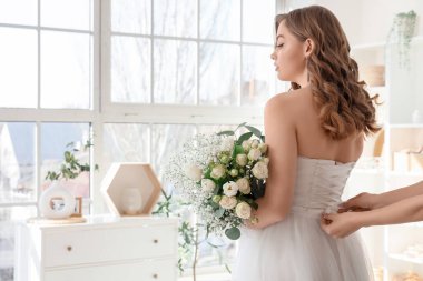 Gelinin korsesini yatak odasında düğün buketi ile bağlayan kadın.