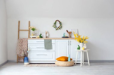 İçinde merdiven, güzel çiçekler, çatal bıçak ve tezgahta Paskalya süslemeleri olan festival mutfağı.