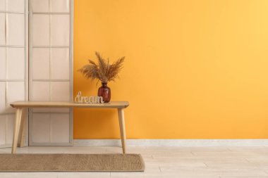 Sarı duvarın yanında katlanır ekran ve bank olan odanın içi