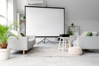 Boş projektör ekranlı, kanepeli ve masalı aydınlık oturma odasının içi