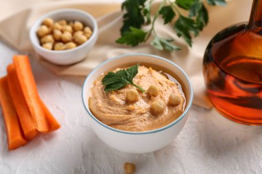 Beyaz arka planda havuçlu, bezelyeli ve maydanozlu lezzetli humus kasesi.