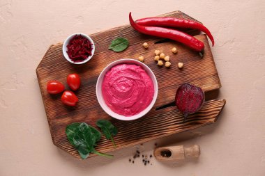 Bir kase lezzetli pancar humusu, domates, biber ve bej arka planda ıspanak.