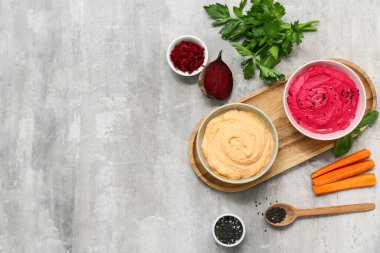 Gri grunge arka planda pancar, maydanoz ve havuçlu farklı lezzetli humus kaseleri.