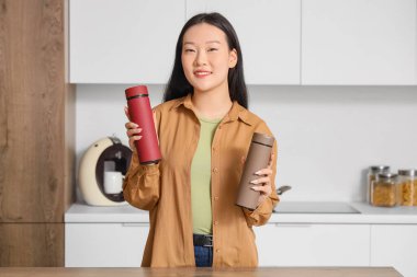 Mutfakta termoslu genç Asyalı kadın.