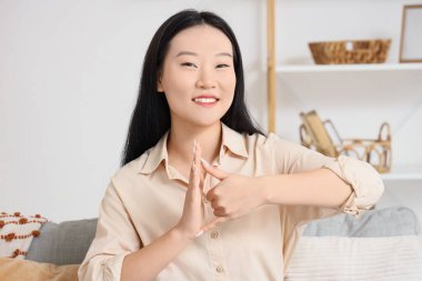 Dilsiz Asyalı kadın evde işaret dili kullanıyor.