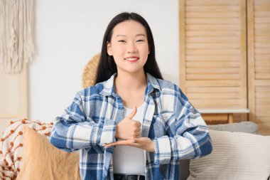 Dilsiz Asyalı kadın evde işaret dili kullanıyor.