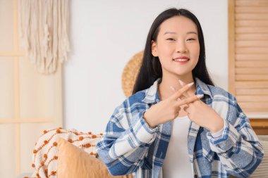 Dilsiz Asyalı kadın evde işaret dili kullanıyor.