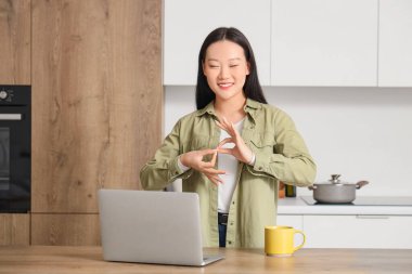 Evdeki video konuşmasında işaret dili kullanan Asyalı kadın.